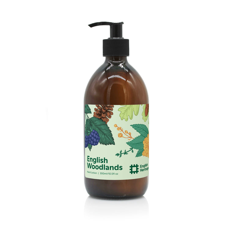 An English Heritage English Woodlands scented moisturising hand and body lotion in amber glass bottle with black lotion pump and woodland illustrated label