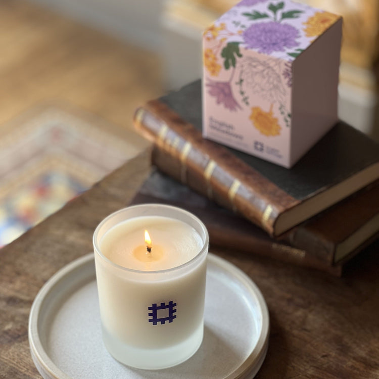 The English Heritage meadows candle is shown lit alongside its box