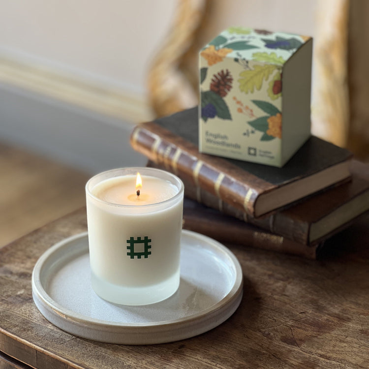 The English Heritage woodlands candle is shown lit alongside its box