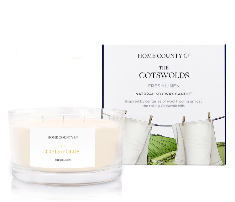 A fresh linen scented 3 wick candle from the Home County Co. is shown next to its eco-friendly candle packaging box.