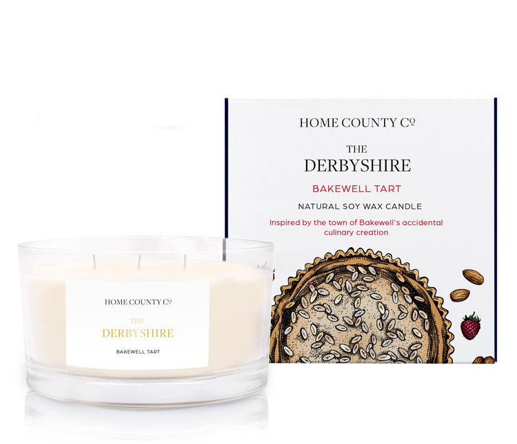 A Bakewell tart scented 3 wick candle from the Home County Co. is shown next to its eco-friendly candle packaging box.