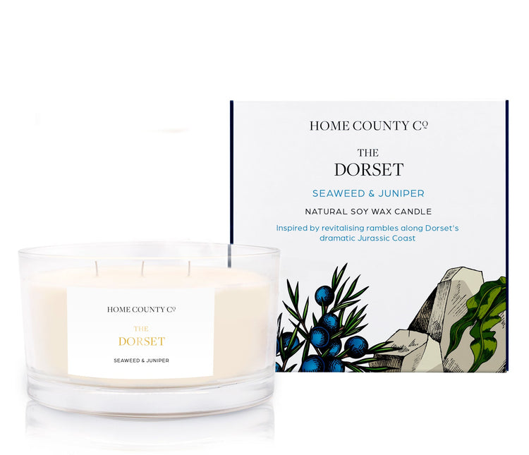 A scotch whisky scented 3 wick candle from the Home County Co. is shown next to its eco-friendly candle packaging box.