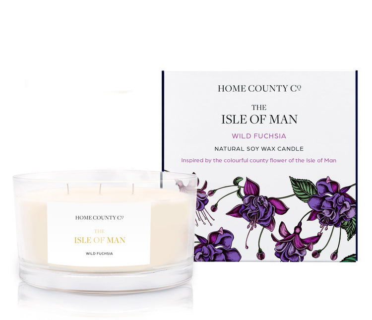 A floral scented 3 cotton wick soy candle from the Home County Co. is scented with wild fuchsia, inspired by the Isle of Man. The natural candle is shown next to its eco-friendly candle box with a floral illustration.