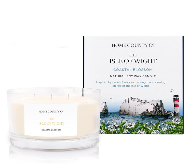 A coastal scented 3 wick soy candle from the Home County Co. is scented with coastal blossom, inspired by the Isle of Wight. The natural candle is shown next to its eco-friendly candle box with a coastline illustration.