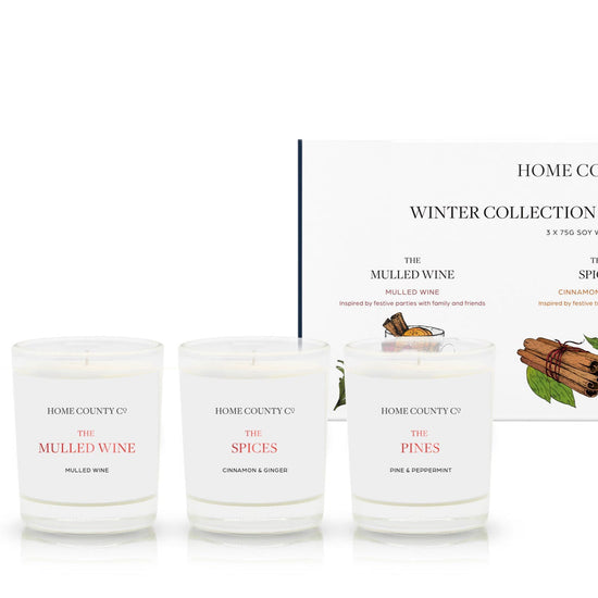 A Christmas candle gift set from the Home County Co. 3 votive soy candles are shown inside their eco-friendly box packaging.