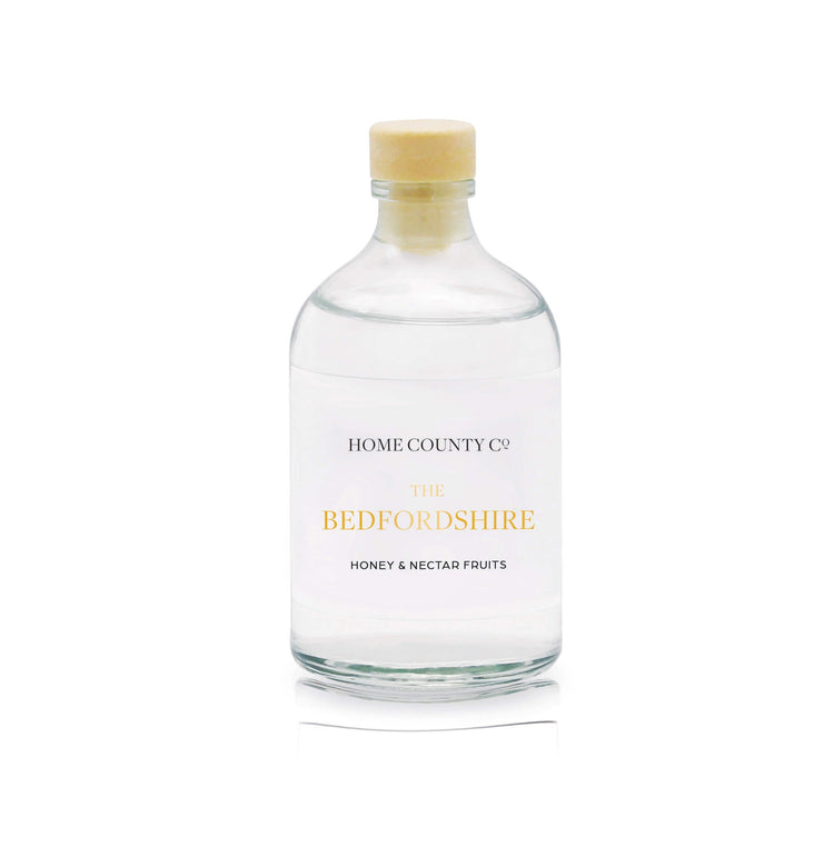 A honey and nectar fruits reed diffuser refill is shown in a recyclable glass bottle