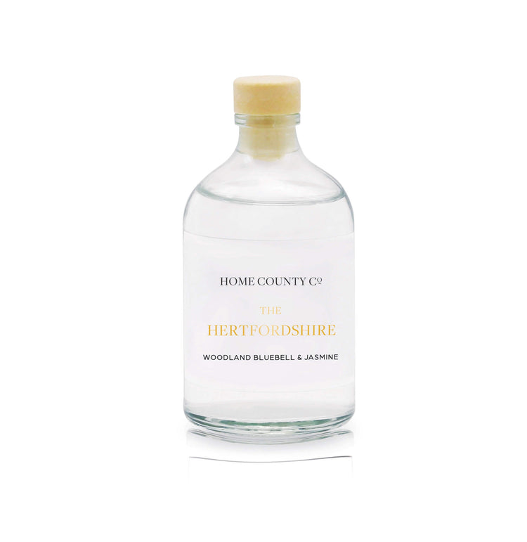 A woodland bluebell and jasmine reed diffuser refill is shown in a recyclable glass bottle