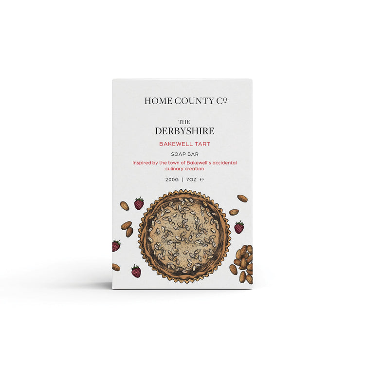 A Bakewell Tart scented natural soap bar from the Home County Co. is shown in its Bakewell Tart illustrated recyclable soap bar wrap
