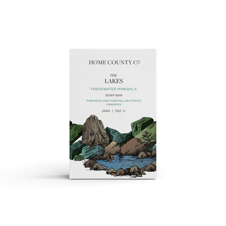 A freshwater minerals scented natural soap bar from the Home County Co. is shown in its Lake District illustrated recyclable soap bar wrap
