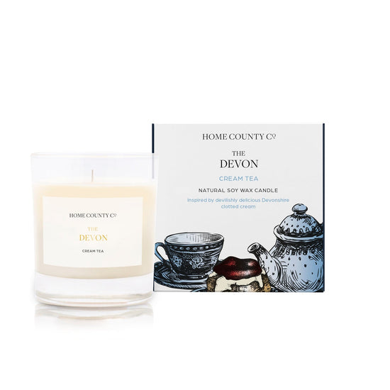 A Devon cream tea scented candle from the Home County Co. is shown next to its eco-friendly illustrated candle box