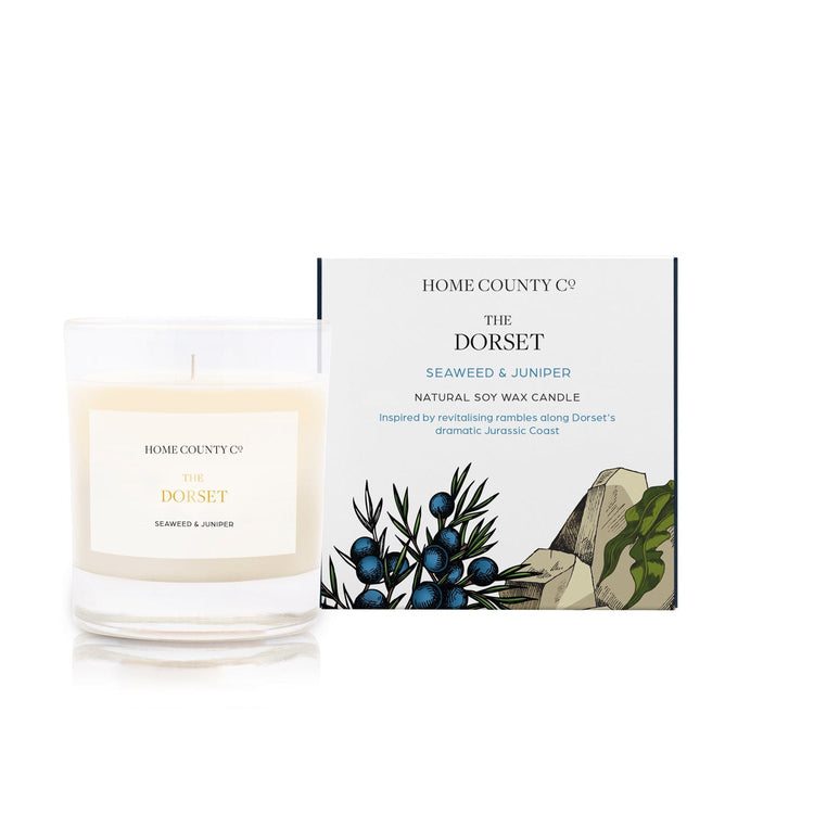A seaweed and juniper coastal scented candle from Home County Co. The cotton wick soy candle is shown next to the eco friendly candle box packaging.