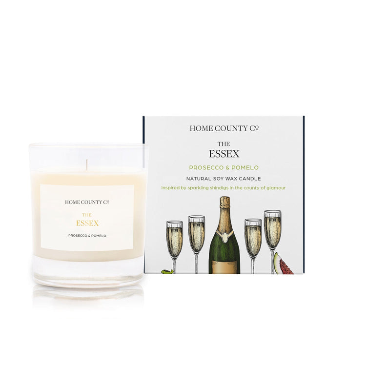A Prosecco and Pomelo scented candle from the Home County Co is shown alight next to the illustrated candle packaging