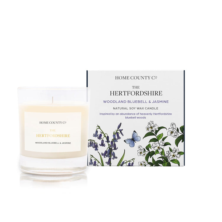 A woodland bluebell and jasmine scented candle from Home County Co. The cotton wick soy candle is shown next to the eco friendly candle box packaging.