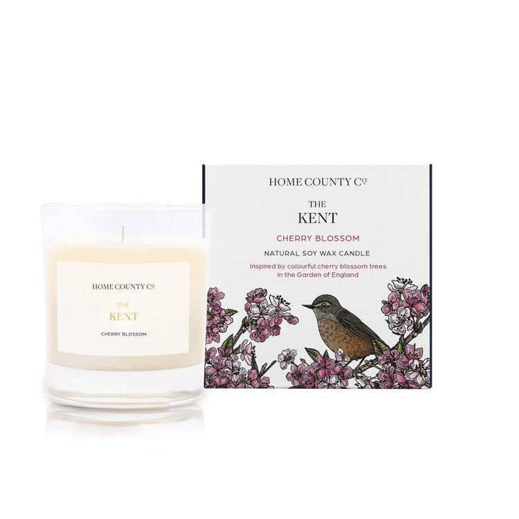 A cherry blossom scented candle from Home County Co. The cotton wick soy candle is shown next to the eco friendly candle box packaging.