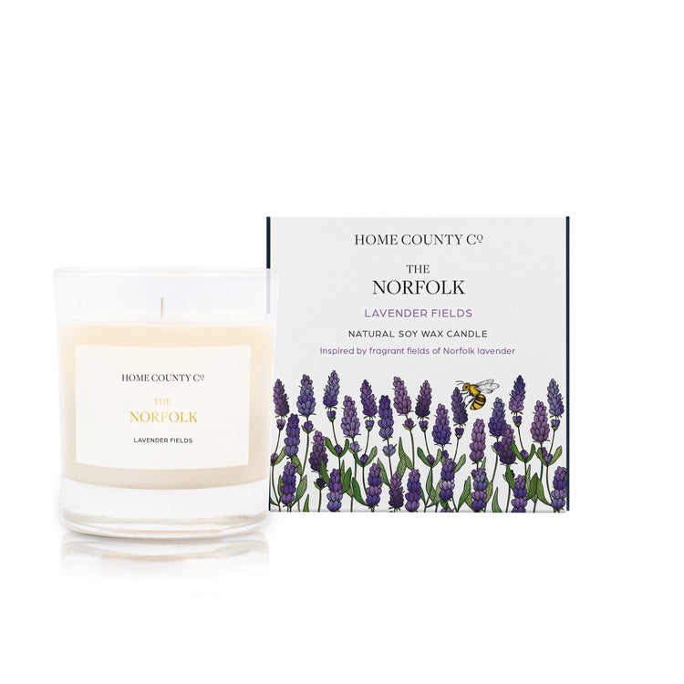 A lavender fields scented candle from Home County Co. The cotton wick soy candle is shown next to the eco friendly candle box packaging.