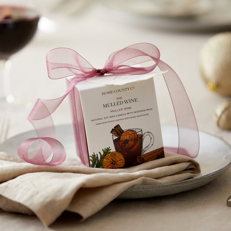 A Mulled Wine scented candle from the Home County Co. is shown alight on a Christmas table