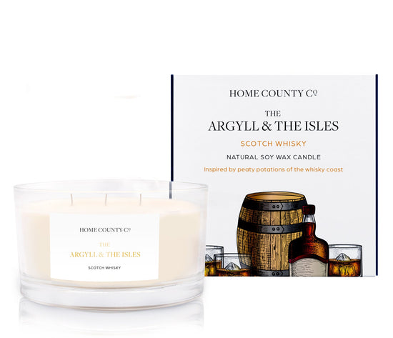 A scotch whisky scented 3 wick candle from the Home County Co. is shown next to its eco-friendly candle packaging box.