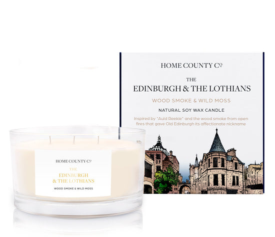 A wood smoke scented 3 wick soy candle from the Home County Co. is inspired by Edinburgh and The Lothians, shown next to its eco friendly candle box.