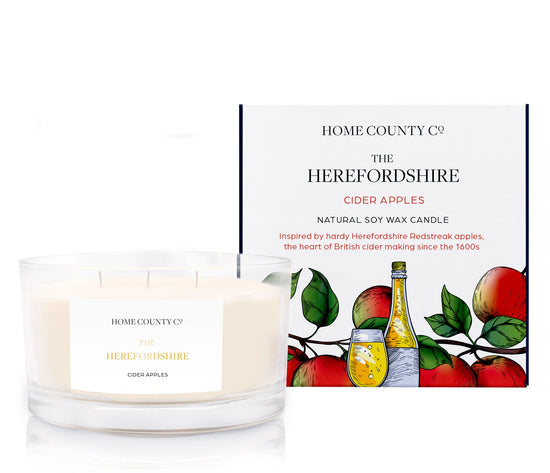 A cider apple scented 3 wick candle from the Home County Co. is shown next to its eco-friendly candle packaging box.