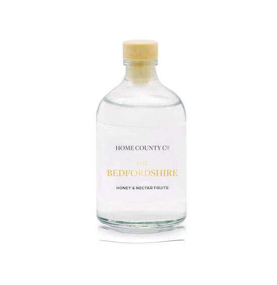 A honey and nectar fruits reed diffuser refill is shown in a recyclable glass bottle