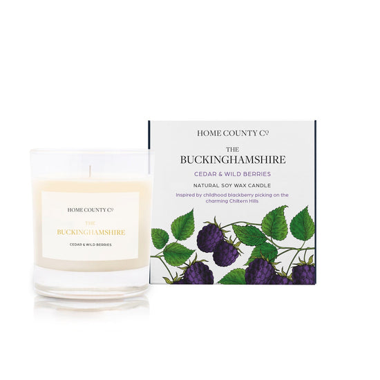 A cedar and wild berries scented candle from Home County Co. The cotton wick soy candle is shown next to the eco friendly candle box packaging.