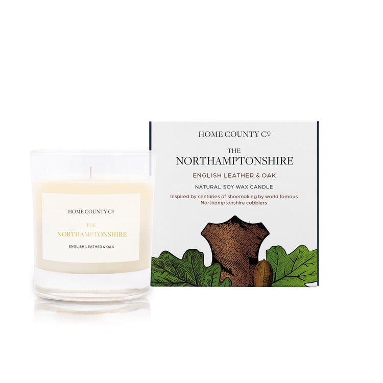 An English leather and oak scented candle from Home County Co. The cotton wick soy candle is shown next to the eco friendly candle box packaging.