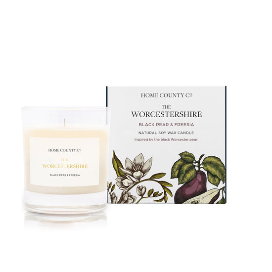 A black pear and freesia scented candle from Home County Co. The cotton wick soy candle is shown next to the eco friendly box packaging.