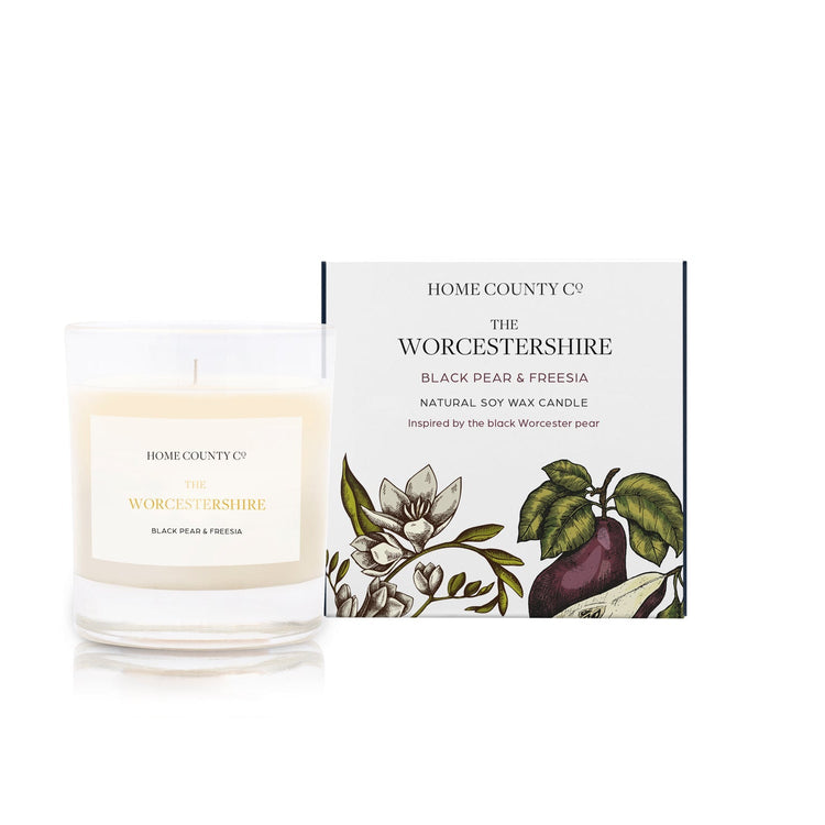 A black pear and freesia scented candle from Home County Co. The cotton wick soy candle is shown next to the eco friendly box packaging.