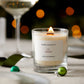 A pine and peppermint scented candle from the Home County Co. is shown alight on a Christmas table 